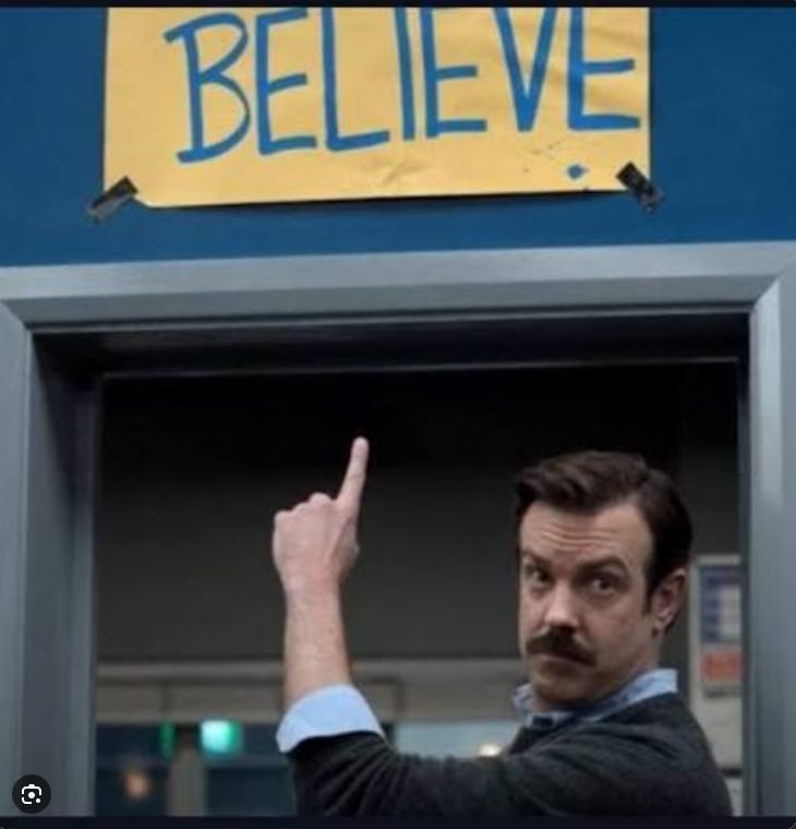 BELIEVE sign with a Ted Lasso-style coach pointing upward